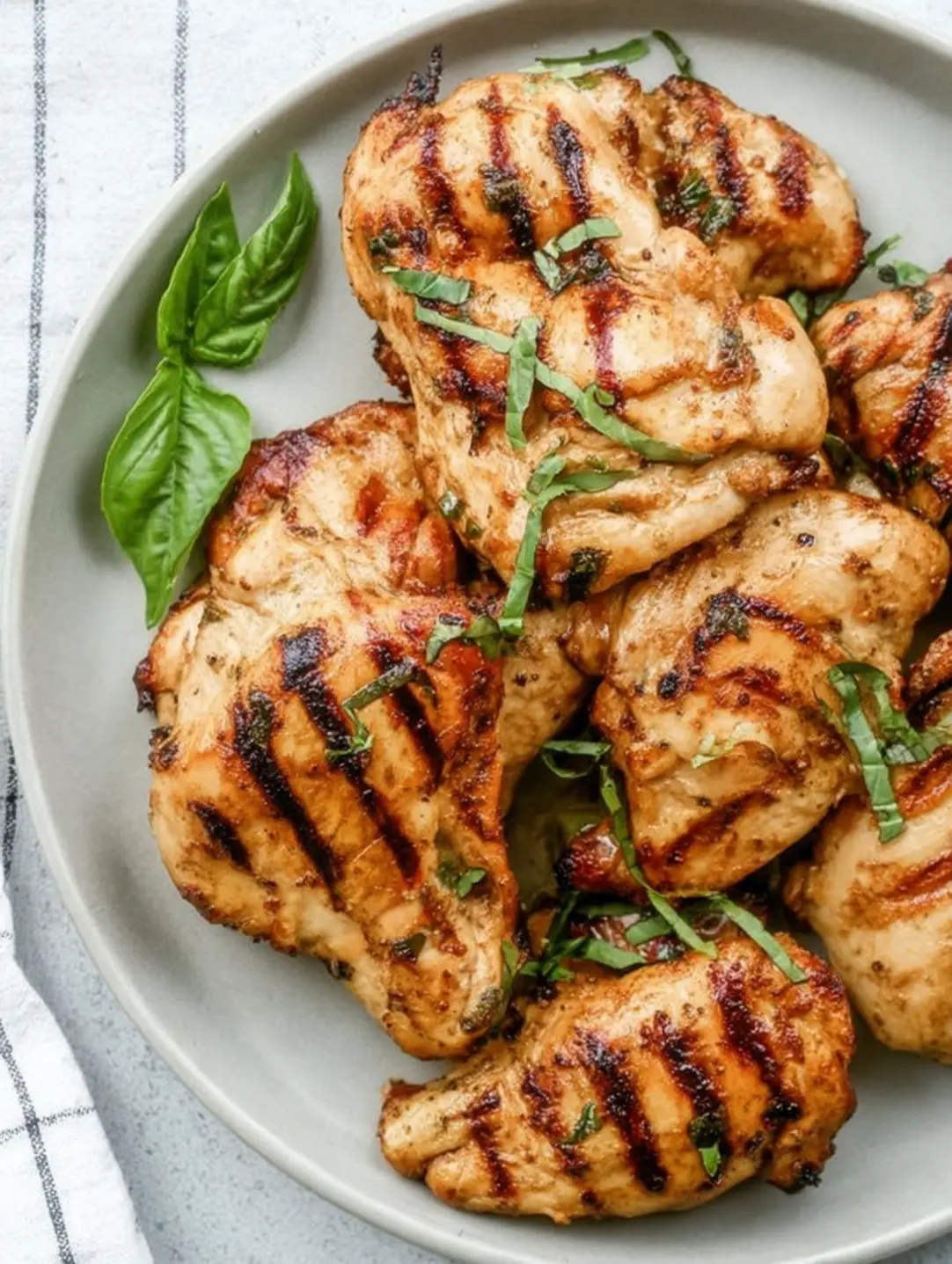 A top-down view of perfectly grilled chicken garnished with fresh basil, an excellent example of easy grilled chicken recipes.