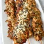 Grilled garlic parmesan chicken skewers coated with herbs and melted parmesan cheese
