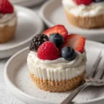 No Bake Cheesecake Cups topped with strawberries, blueberries, raspberries, and whipped cheesecake filling