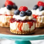 No-Bake Mini Cheesecakes topped with blueberries, raspberries, whipped cream, and berry sauce