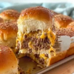 Oven-baked cheeseburger sliders with melted cheddar cheese on soft sesame buns